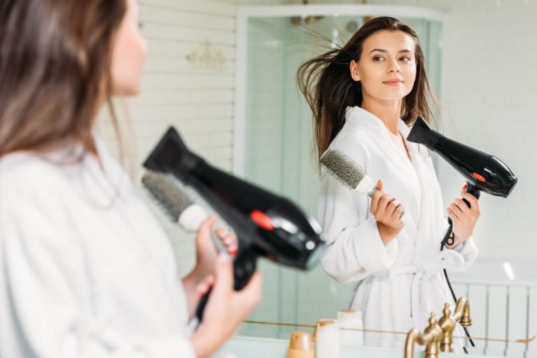 Femme utilisant une brosse brushing devant un miroir.