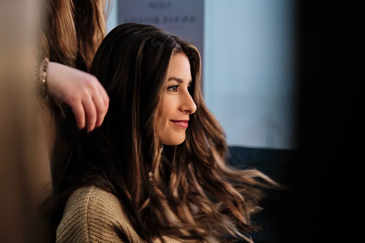 Femme aux cheveux bouclés appliquant une crème coiffante pour hydrater et définir ses boucles
