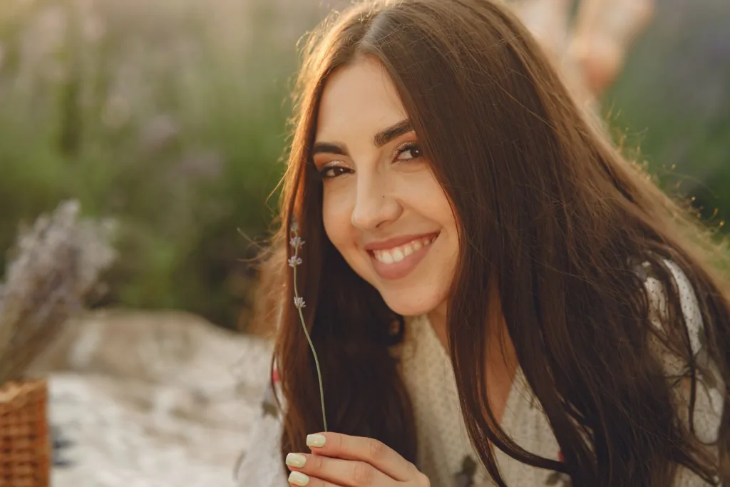 Femme souriante aux longs cheveux bruns brillants dans une lumière chaude