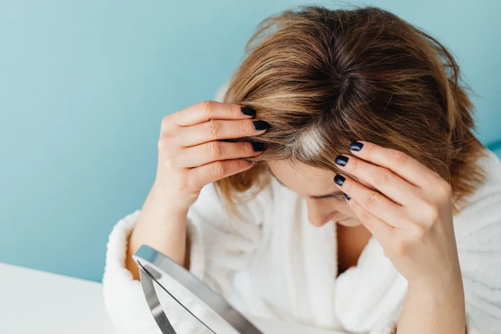 Femme qui examine ses racines dans un miroir