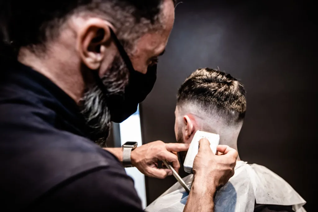 Barbier qui réalise un dégradé précis sur un client