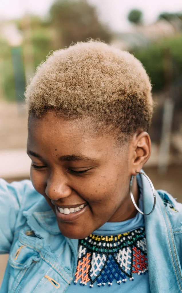 Femme souriante avec un afro très court décoloré en blond