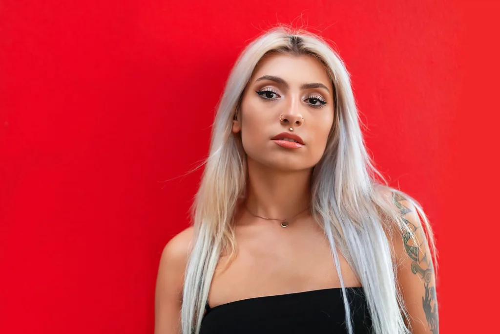 Femme aux cheveux blond platine décolorés sur fond rouge