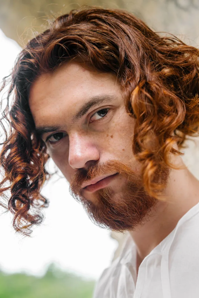 Homme aux cheveux bouclés mi-longs qui tombent sous la mâchoire