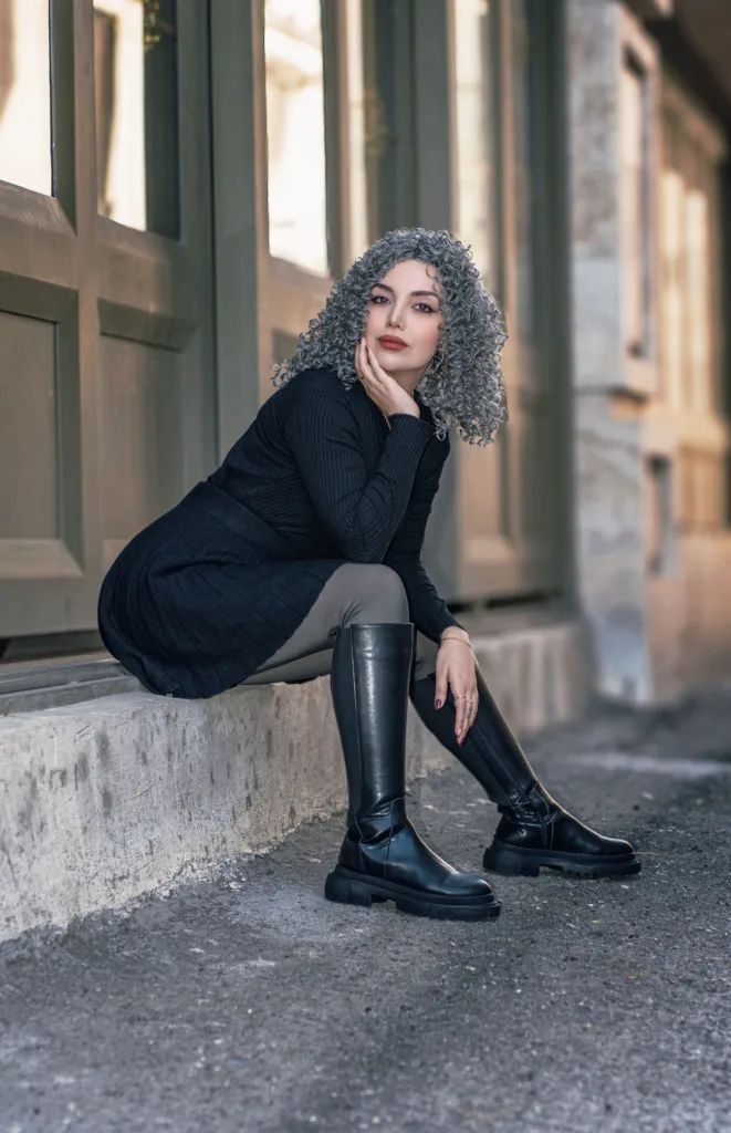 Femme aux cheveux gris bouclés assise en ville
