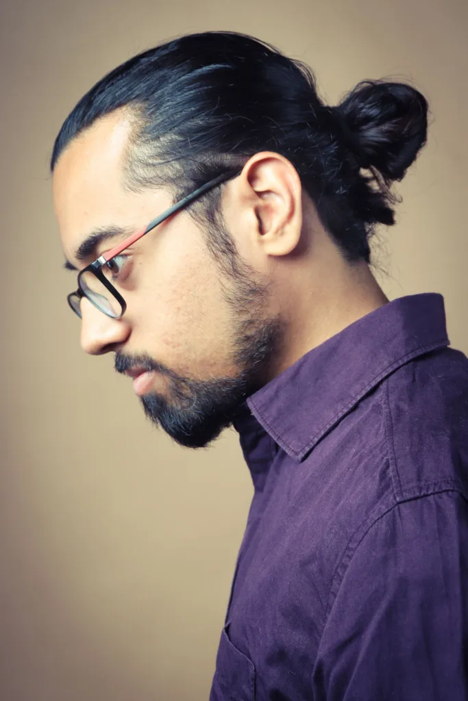 Homme aux cheveux longs attachés en chignon, lunettes