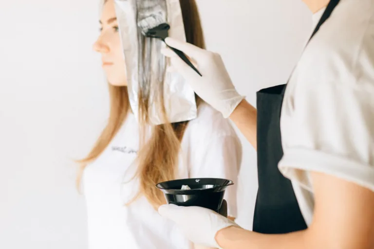 Coiffeuse appliquant une coloration au pinceau sur des cheveux blonds en salon