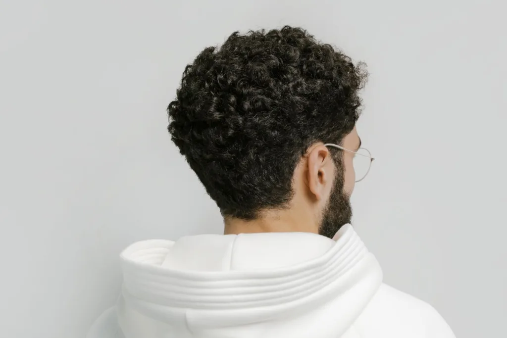 Homme vu de dos avec une coupe courte bouclée arrondie et une nuque naturelle