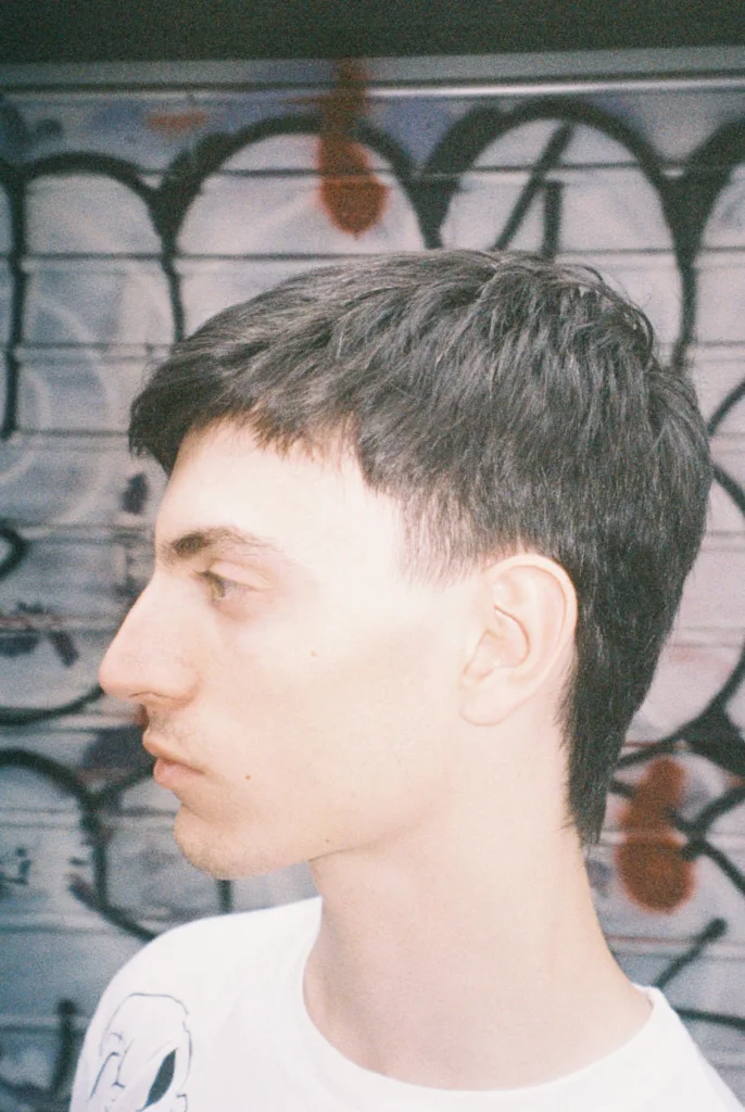 Jeune homme de profil avec un mulet court et une frange