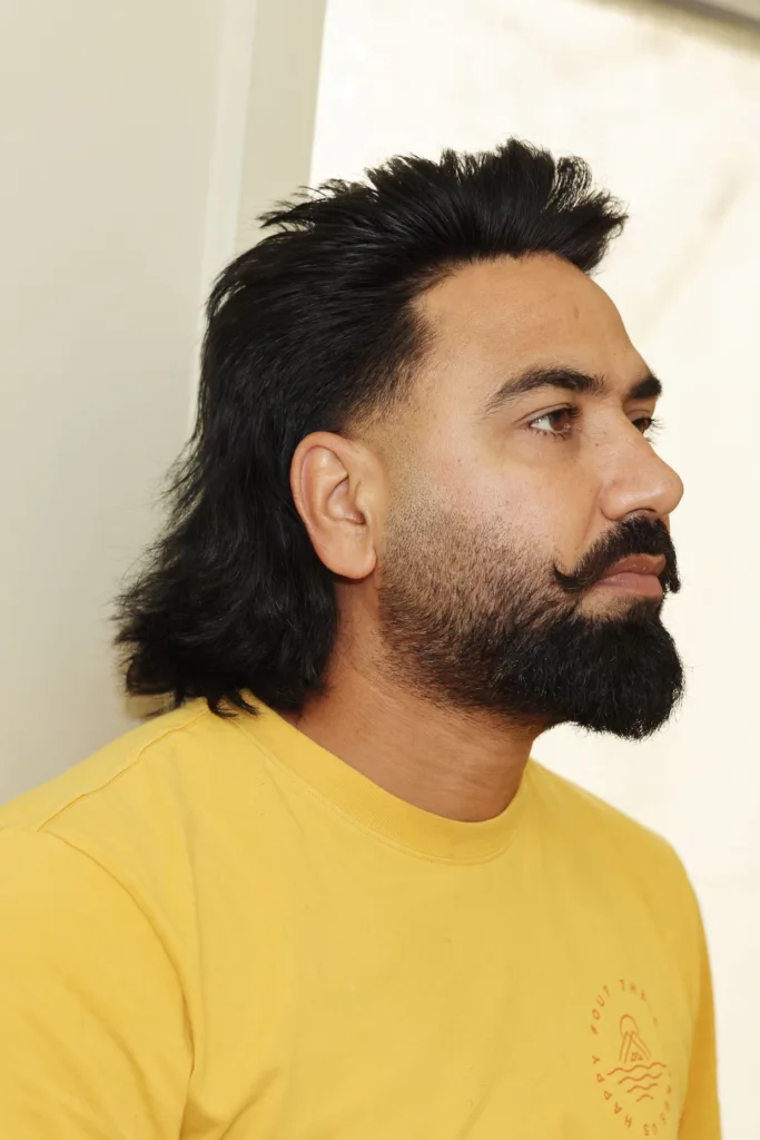 Homme barbu avec un mulet aux longueurs ondulées dans la nuque