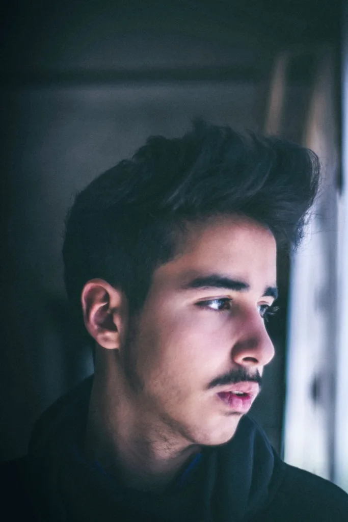 Homme de profil avec une coupe quiff : volume relevé sur le devant, côtés courts
