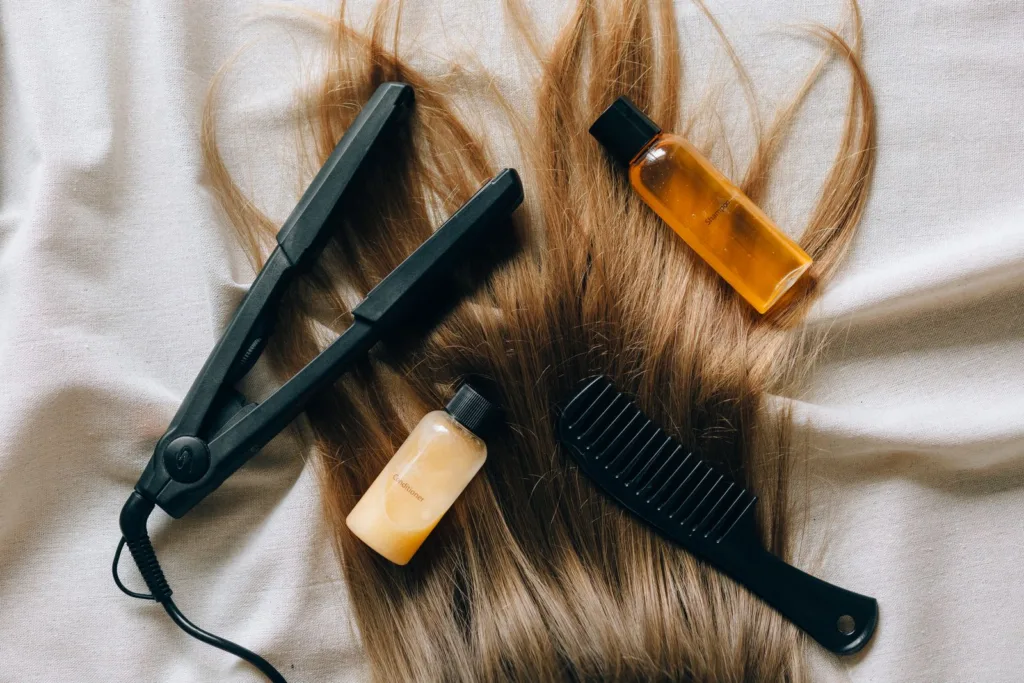 Fer à lisser, peigne et soins posés sur des cheveux longs