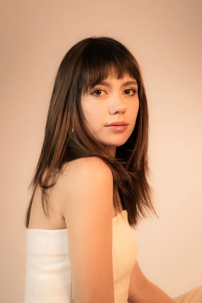 Femme aux cheveux mi-longs avec une frange rideau ouverte sur le front