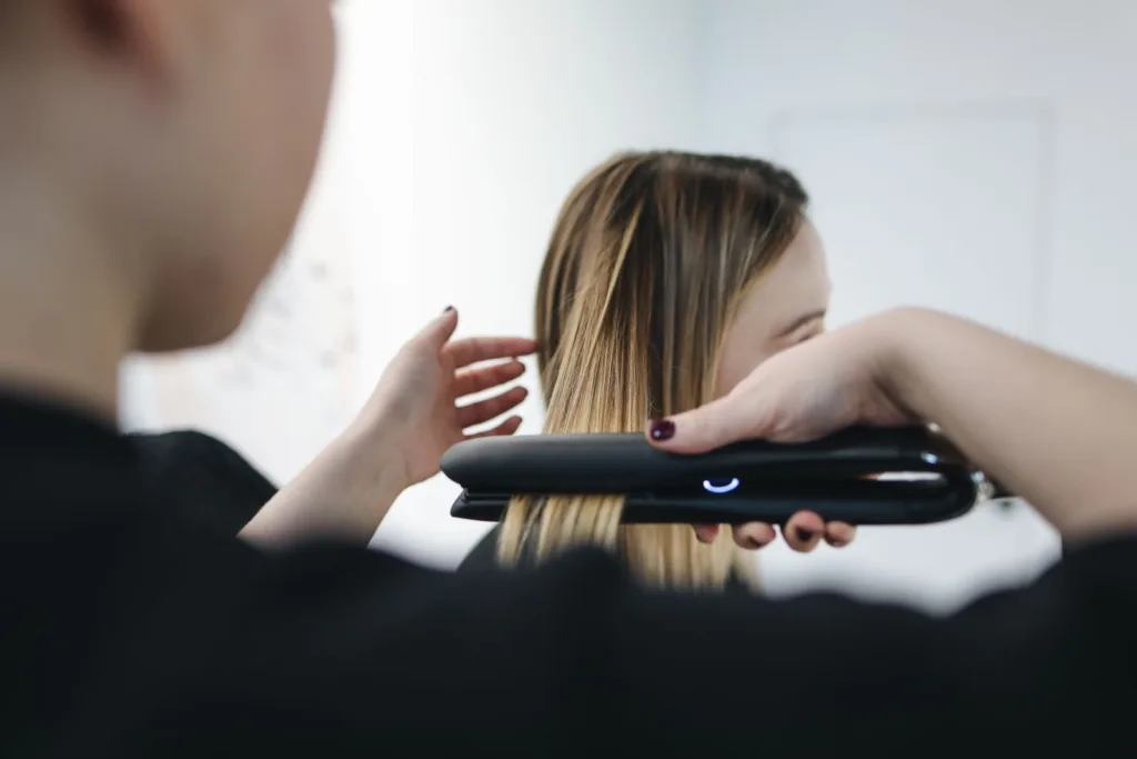 Lissage d'une mèche blonde au fer à lisser par un coiffeur