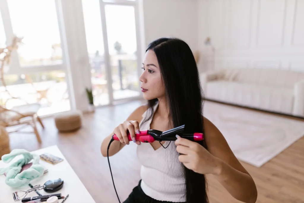 Femme qui lisse ses cheveux longs bruns à la maison