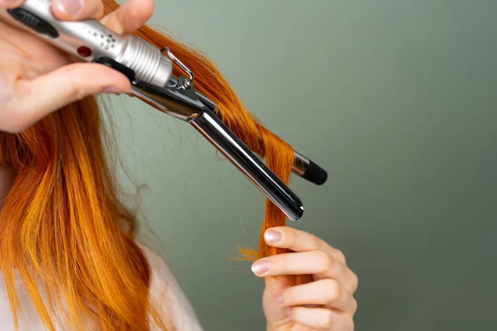 Mèche rousse enroulée autour d'un fer à boucler