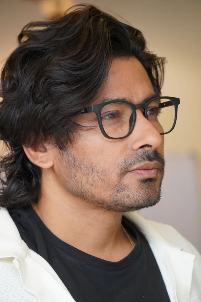 Homme à lunettes avec des cheveux mi-longs coiffés sur le côté