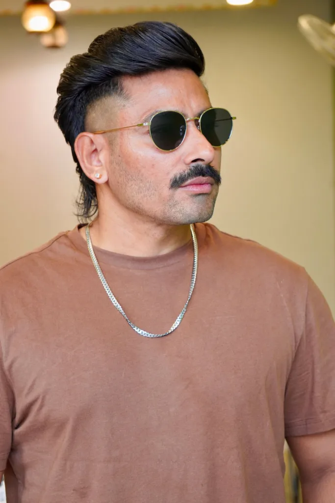 Homme avec un mulet et une moustache : dessus coiffé en arrière, côtés rasés en dégradé, nuque plus longue