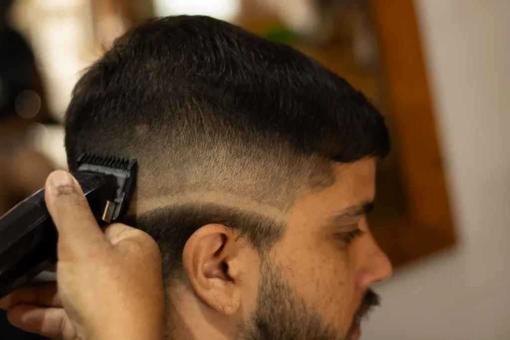 Barbier qui trace une raie à la tondeuse au-dessus d'un dégradé