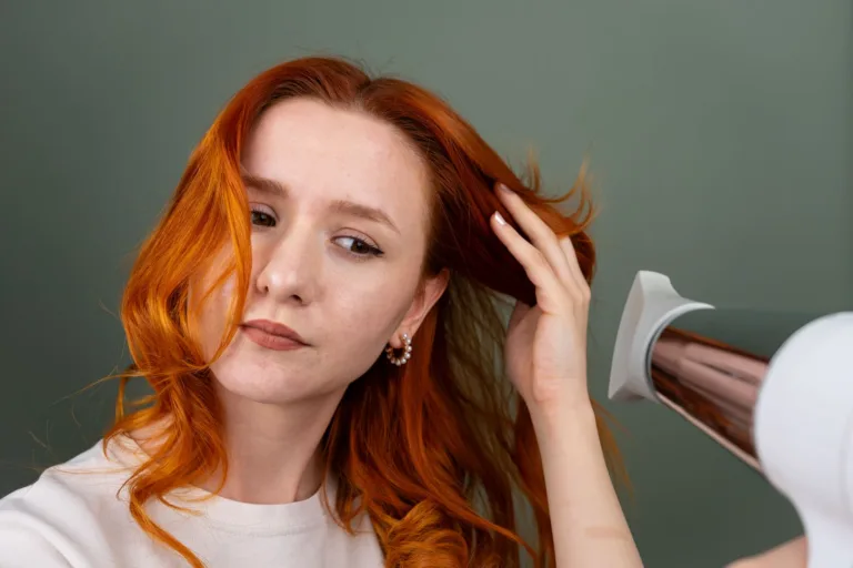 Femme séchant ses cheveux longs roux au sèche-cheveux