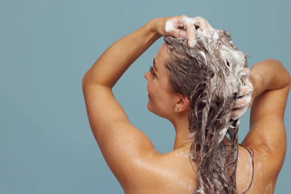 Femme faisant mousser un shampoing sur ses cheveux longs