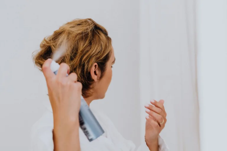 Femme qui vaporise un shampoing sec en aérosol sur ses racines