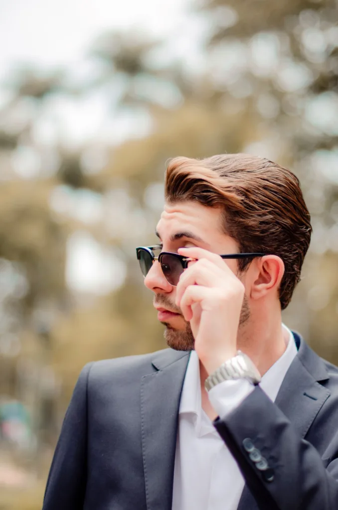 Homme avec les cheveux coiffés en arrière, lunettes de soleil et costume