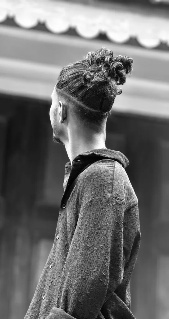 Homme de dos avec les côtés rasés et les longueurs du dessus attachées en chignon